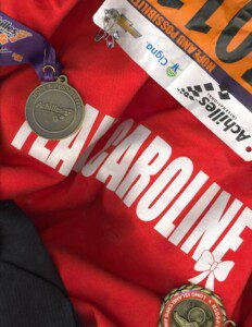 Caroline, a young adult photographer with CRPS, depicts her team shirt for the awareness walks she has participated in along with her medals