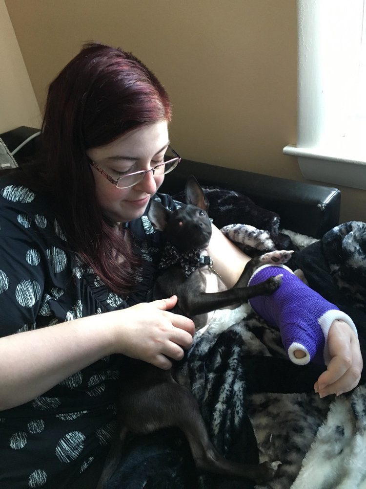 Woman with a cast who is also holding her dog.