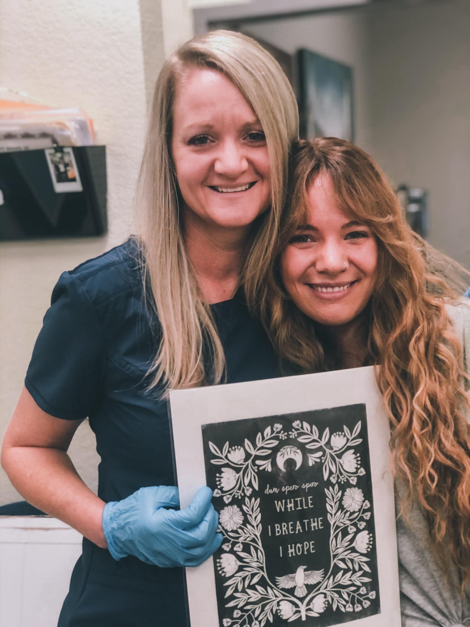 Two women smiling while one is holding art